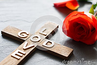 Easter christian wooden cross with an inscription god is love and red rose abstract religion background Stock Photo