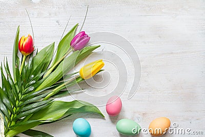 Easter colorful spring tulips with palm and eggs decoration on white wooden natural background Stock Photo