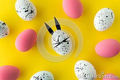 Easter composition with colored eggs and egg with bunny ears and face on yellow background Stock Photo