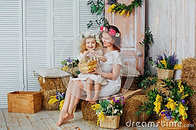 Easter composition. Mother and daughter in white dresses and flower wreaths on their heads play with ducklings. Farm village Stock Photo