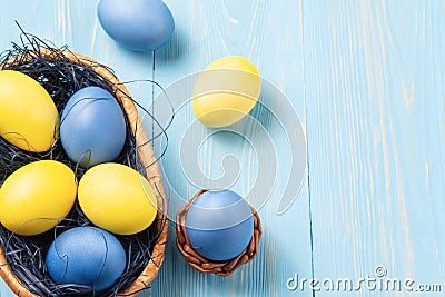 Easter composition - several colored eggs in a basket on a blue wooden table, place for text, copy space Stock Photo