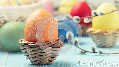 Easter composition - several colored eggs in a basket and on a blue wooden table with willow twigs Stock Photo