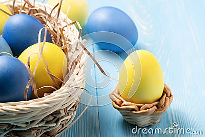 Easter composition - several colored eggs in a basket and stand on a blue wooden table Stock Photo