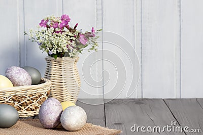 Easter composition - several eggs painted with natural dyes and wildflowers in a vase Stock Photo