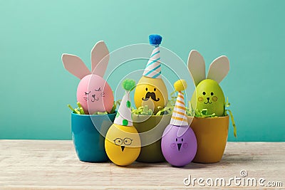Easter concept with cute handmade eggs in coffee cups, bunny, chicks and party hats Stock Photo