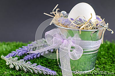 Easter concept - the egg in a decorative pail on the grass with Decker on a bright background Stock Photo