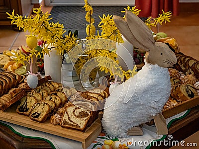 Easter decoration with rabbit, yellow flowers and plates with tasty cake and fruit Stock Photo
