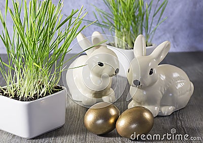 Easter decoration rabbits and golden eggs on a gray wooden back Stock Photo