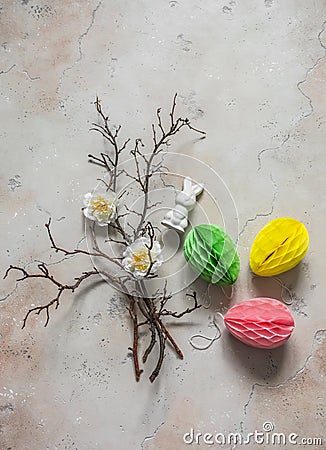 Easter decoration - tree branches, paper colored eggs, flowers, ceramic easter rabbit on a light background, top view. Handmade Stock Photo