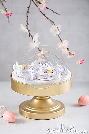 Easter dessert table. Pavlova mini nests with candy eggs and a flowering branches on white background. Side view. Easter greeting Stock Photo
