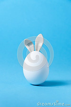 Easter Egg with Bunny Ears on Blue Background. Creative Greeting Card. Minimalism Concept. Copy Space Stock Photo