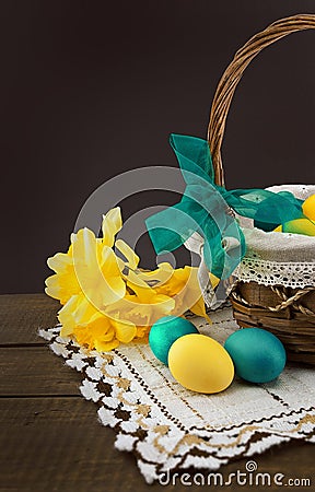 Easter eggs in the basket on wooden table with bouquet of daffodil Stock Photo