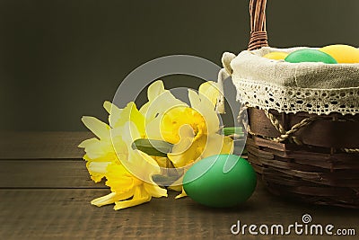 Easter eggs in the basket on wooden table with bouquet of daffodil Stock Photo