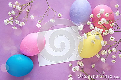 Easter eggs with blank paper card and white flowers on purple ba Stock Photo