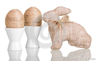 Easter eggs in cups with string entwined and bunny isolated. Stock Photo