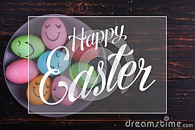 Easter eggs with cute faces on the plate. Preparing for the holiday on the kitchen table, on a dark background. Text, happy easter Stock Photo