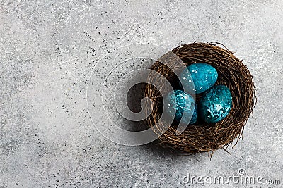 Easter eggs in nest painted by hand in blue color on light background Stock Photo