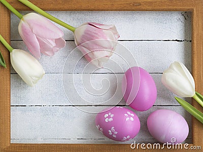 Easter eggs, photo frame, tulips on a white wooden background Stock Photo