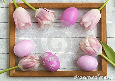 Easter eggs, photo frame, tulips on a white wooden background Stock Photo