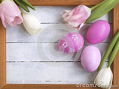 Easter eggs, photo frame, tulips on a white wooden background Stock Photo