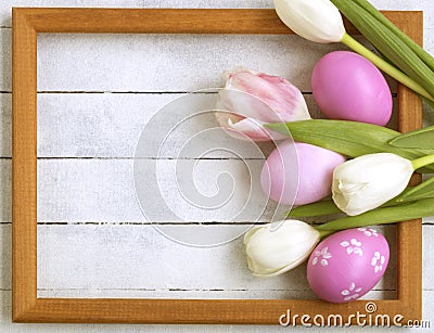 Easter eggs, photo frame, tulips on a white wooden background Stock Photo