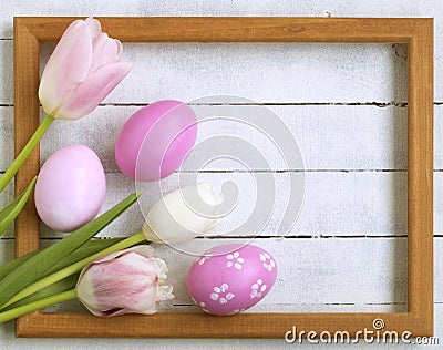 Easter eggs, photo frame, tulips on a white wooden background Stock Photo