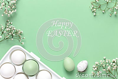 Easter eggs in a white holder and spring flowers on a green background. Copy space Stock Photo