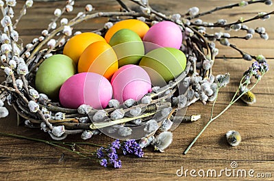 Easter eggs in willow nest, flowers over wooden rustic background Stock Photo