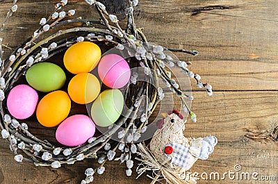 Easter eggs in willow nest, flowers over wooden rustic background Stock Photo