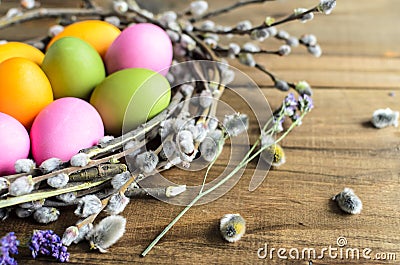 Easter eggs in willow nest, flowers over wooden rustic background Stock Photo