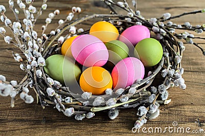 Easter eggs in willow nest, flowers over wooden rustic background Stock Photo