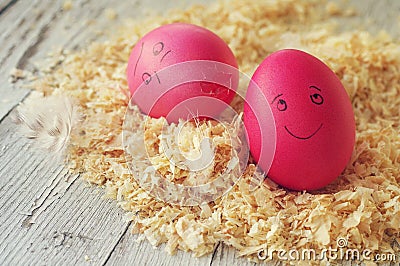 Easter eggs on wood sawdust. Two amusing Easter eggs with the drawn persons. Stock Photo