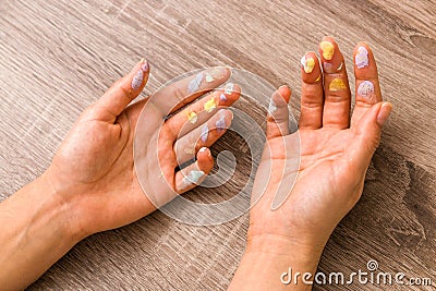 Easter and feminity concept. closeup woman hands dirty by goache paint with multicolor spots over a wooden table Stock Photo