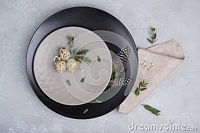 Easter festive table setting with gray plate, quail eggs leaf sprigs of eucalyptus. Stock Photo