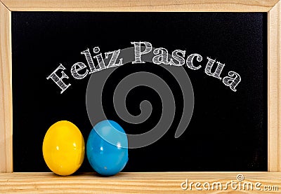 Easter frame with painted eggs and chalkboard. Happy Easter in white chalk. Happy Easter in spanish : feliz Pascua Stock Photo