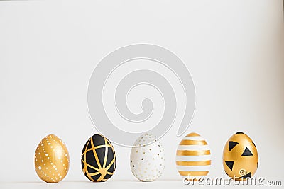 Easter golden decorated eggs stand in a row on white background. Minimal easter concept. Stock Photo