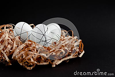 Easter goldenand white decorated eggs in nest on black background . Minimal easter concept copy space for text. Top Stock Photo