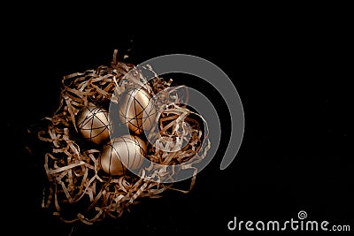 Easter goldenand white decorated eggs in nest on black background . Minimal easter concept copy space for text. Top Stock Photo