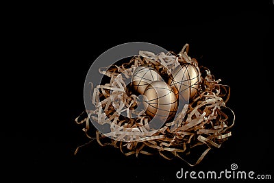 Easter goldenand white decorated eggs in nest on black background . Minimal easter concept copy space for text. Top Stock Photo