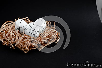 Easter goldenand white decorated eggs in nest on black background . Minimal easter concept copy space for text. Top Stock Photo