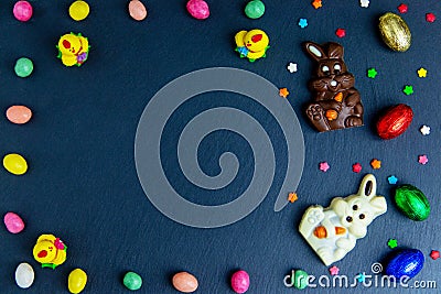 Easter greeting card with colorful candy frame, chocolate eggs and candies. Top view on stone table with space for your greetings Stock Photo