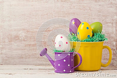 Easter holiday concept with egg decoration in yellow cup and watering can Stock Photo