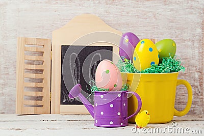 Easter holiday concept with painted eggs decoration, cup and watering can Stock Photo