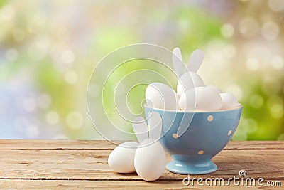 Easter holiday eggs with bunny ears on wooden table over garden bokeh background Stock Photo