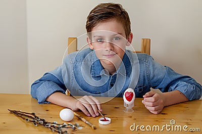 Easter Holiday at Home. Young blonde boy coloring drawing Easter Eggs Stock Photo