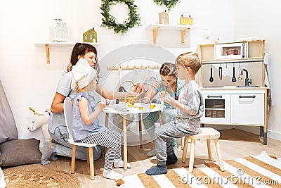 Easter holiday: mother and children sit at the table and paint eggs with paints. Stock Photo