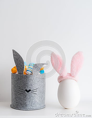 Easter minimalistic decor in the interior. A gray felt basket in the shape of a hare and a large ceramic egg with ears Stock Photo