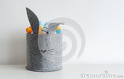 Easter minimalistic decor in the interior. A gray felt basket in the shape of a hare and a large ceramic egg with ears Stock Photo