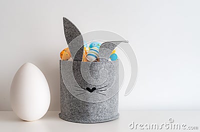 Easter minimalistic decor in the interior. A gray felt basket in the shape of a hare and a large ceramic egg with ears Stock Photo