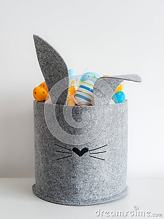 Easter minimalistic decor in the interior. A gray felt basket in the shape of a hare and a large ceramic egg with ears Stock Photo